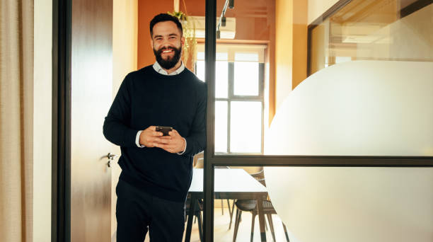 istock Successful businessman smiling while holding a smartphone 1358737168