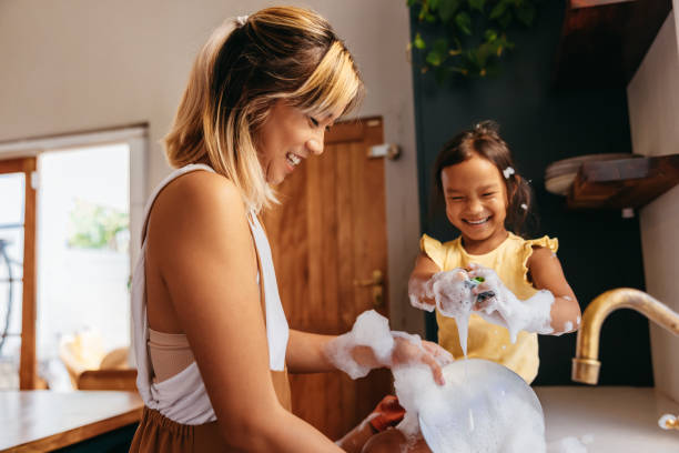 mãe e filha felizes lavando pratos na cozinha - afazeres domésticos - fotografias e filmes do acervo