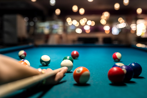 close up of female hand hold cue and preparing aiming to shoot to pool balls. game concept