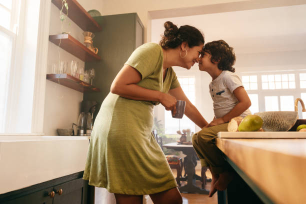 affectionate mother touching noses with her young son - keuken huis fotos stockfoto's en -beelden
