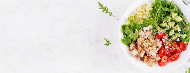 Grilled chicken fillet and fresh vegetable salad of lettuce, arugula, cucumber tomato and cheese. Healthy lunch menu. Diet food. Top view, banner stock photo