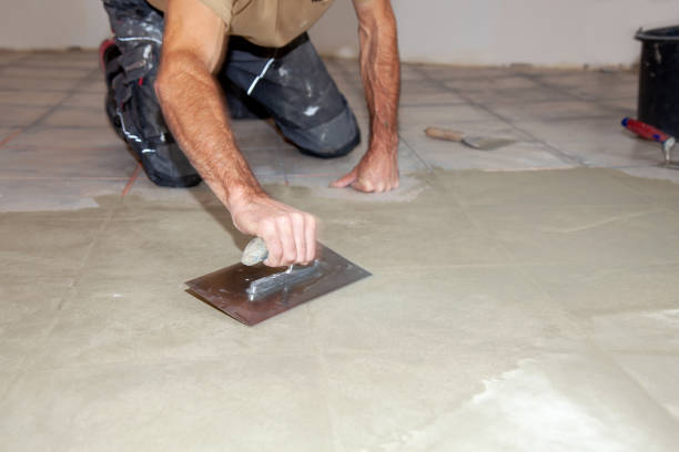 istock Construction worker leveling compound with putty knife. Renovation, floor leveling screed, mass distribution. 1358739316