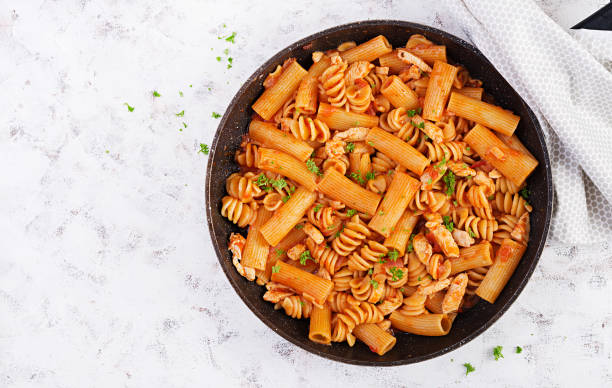 istock Fusilli pasta in tomato sauce with chicken, tomatoes decorated with parsley on light table. Top view 1358739384