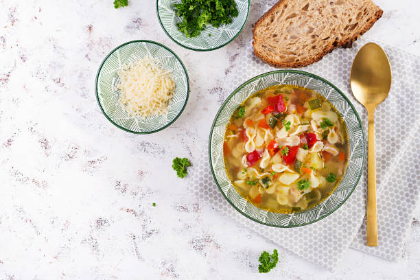 istock Minestrone, italian vegetable soup with pasta on light table. Top view, flat lay 1358739442