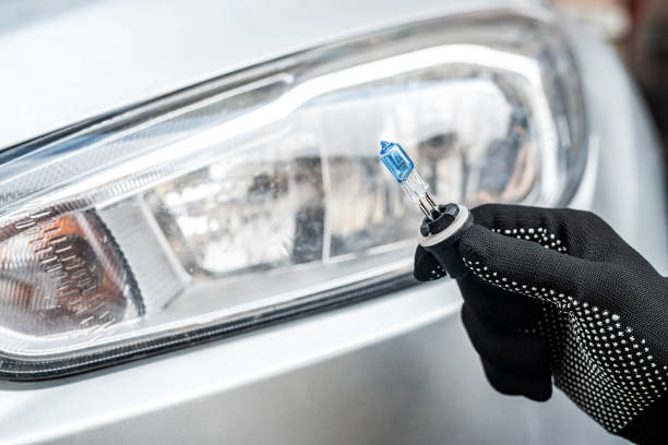 istock Car service men holding halogen h7 lamp for change in headlight 1358740028