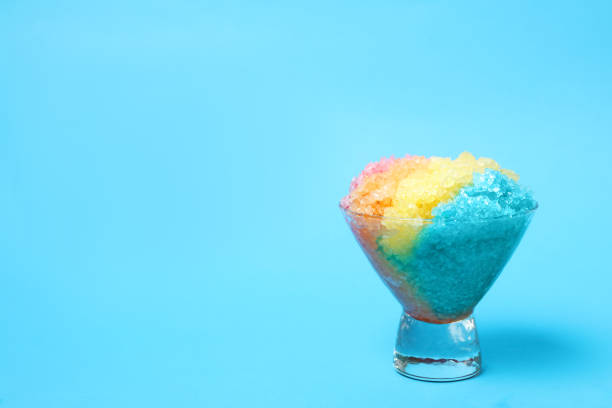 istock Rainbow shaving ice in glass dessert bowl on light blue background, space for text 1358740226