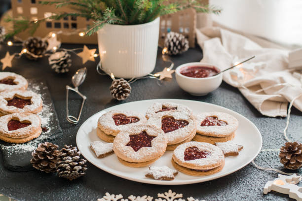 istock Ready Linzer cookies with berry jam on a plate and Christmas decorations on a dark background. Cooking Christmas treats. Lifestyle 1358740228
