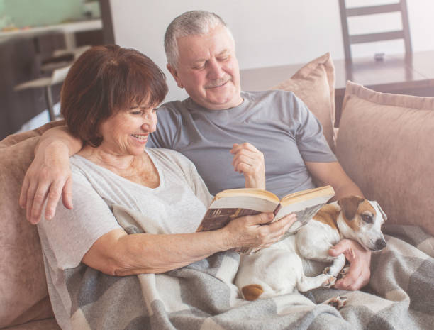 istock Happy elderly couple sitting on sofa at home 1358740515