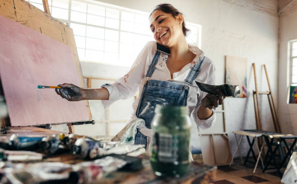 istock Freelance painter taking a phone call in her art studio 1358740530