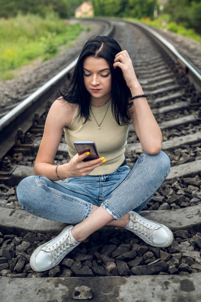 istock brunette young woman standing on on a railway tracks 1358740535