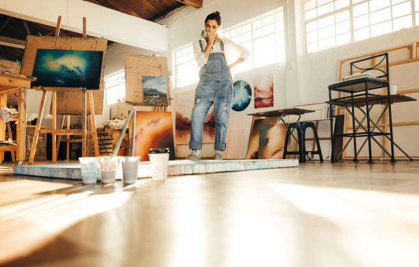 istock Thoughtful female painter looking at her painting 1358740599