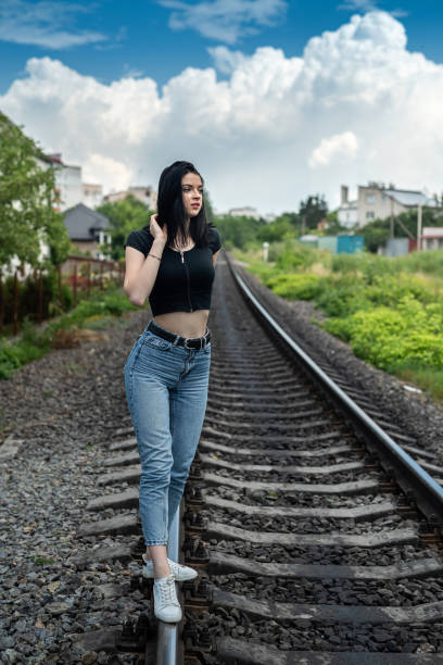 Young woman standing on a railroad, travel by train in summer holiday.