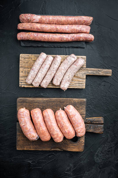 istock Assorted raw homemade sausages, flat lay, on black background 1358741910
