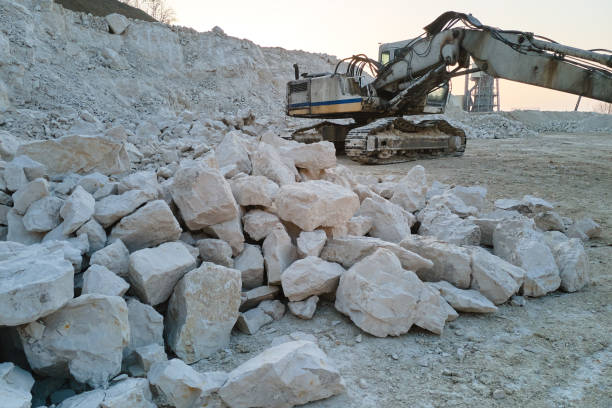 Open pit mining site of construction sand stone materials with excavator equipment for digging of gravel resources at quarry.