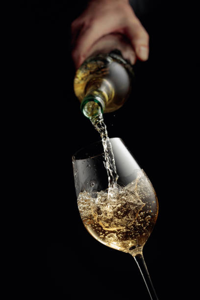 istock Pouring white wine in a glass goblet. 1358743574
