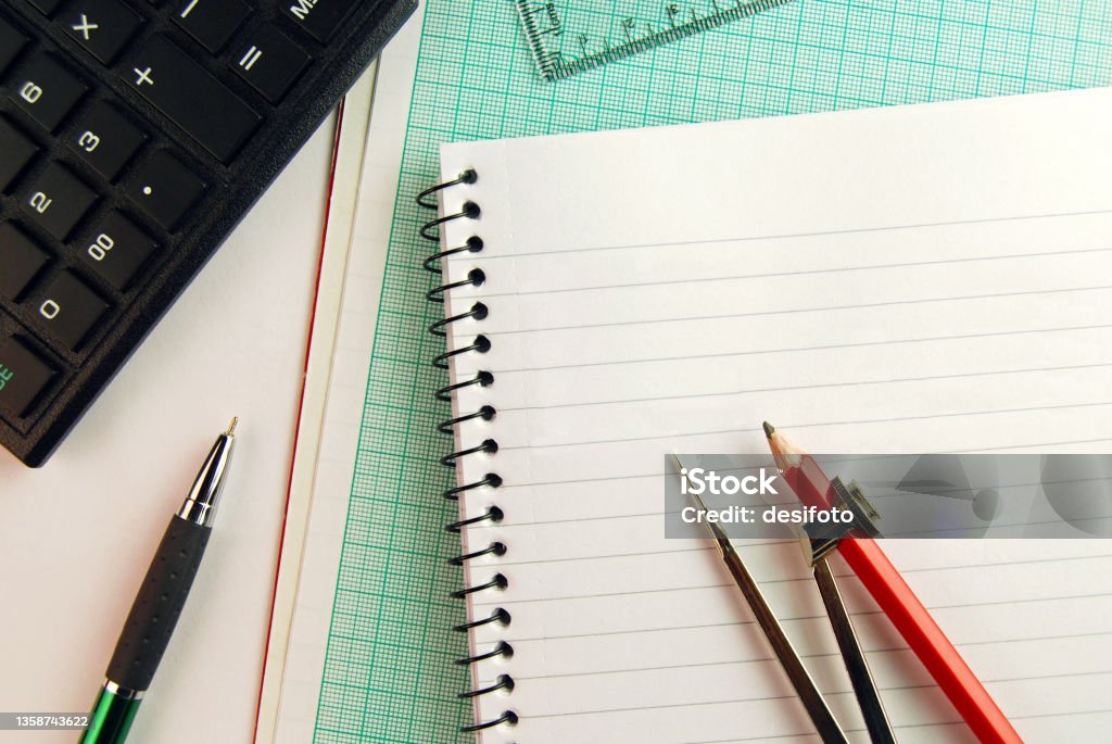 Geometry tools - An open compass placed over a page of a spiral notepad and graph paper, with calculator and set square in the hindsight. Geometry tools - An open compass placed over a page of a spiral notepad and graph paper, with calculator and set square in the hindsight. There is no people, no text and copy space. Set Square Stock Photo