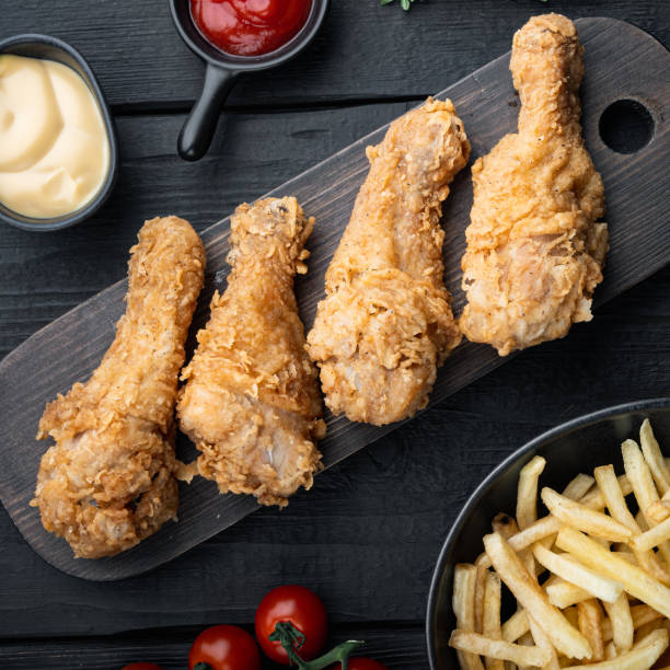 istock Breaded kentucky chicken drumctick on black wooden background, flat lay 1358744075