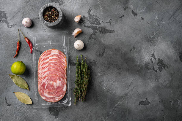 istock Dry sliced sausages packed in vacuum plastic, on gray stone table background, top view flat lay, with copy space for text 1358744149