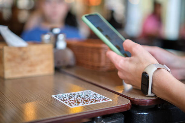 primer plano del huésped ordenando comida a mano en el restaurante mientras escanea el código qr con el teléfono móvil para el menú en línea. - dinner currency table business fotografías e imágenes de stock