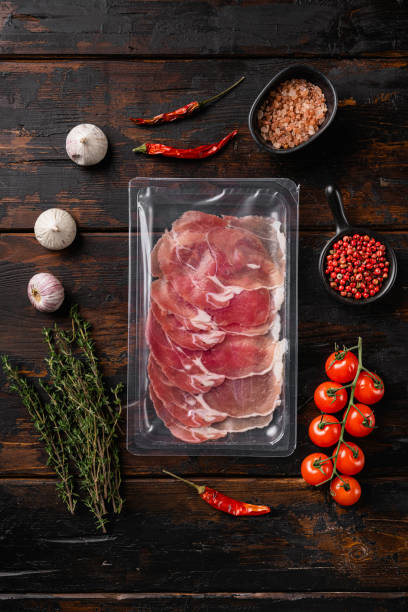 istock Cured ham jamon vacuum plastic pack, on old dark  wooden table background, top view flat lay 1358746061
