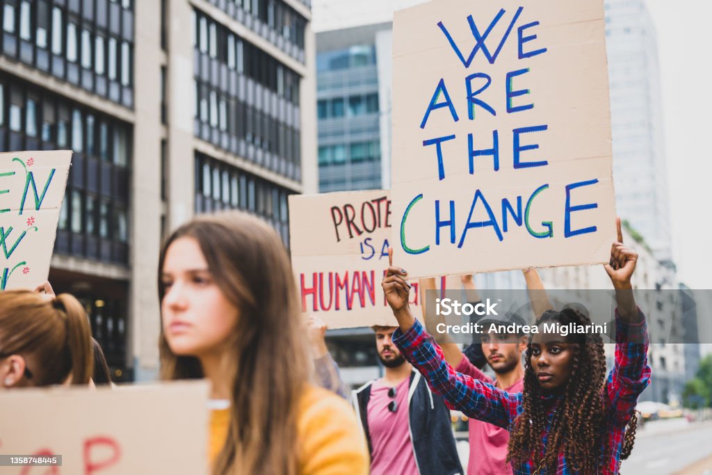 people strike against climate change and pollution, young african woman holding a poster communicating we are the change Protest Stock Photo