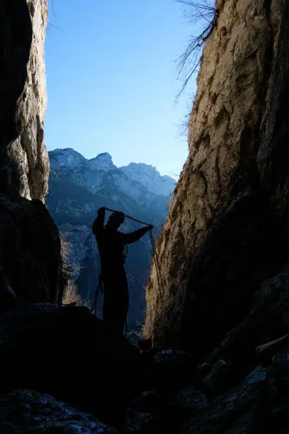 Silhouette of a climber coiling a rope in a narrow gully/canyon