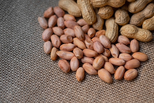 Close-up shot of fresh peanuts group with shelled peanuts on wicker floor