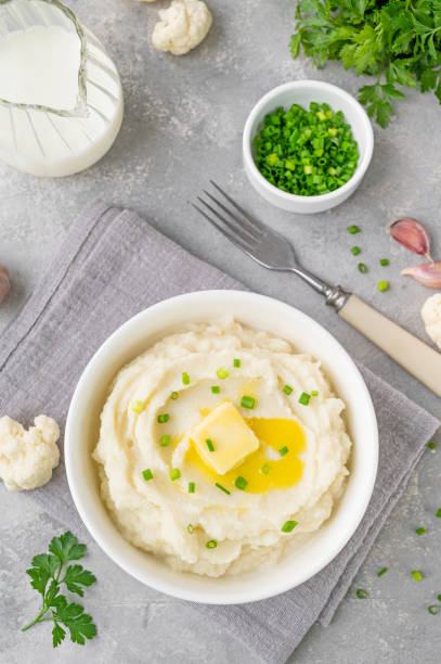 Cauliflower puree with butter and green onions in a white bowl on a gray concrete background. Healthy food. Copy space. Cauliflower puree with butter and green onions in a white bowl on a gray concrete background. Healthy food. Copy space mashed stock pictures, royalty-free photos & images