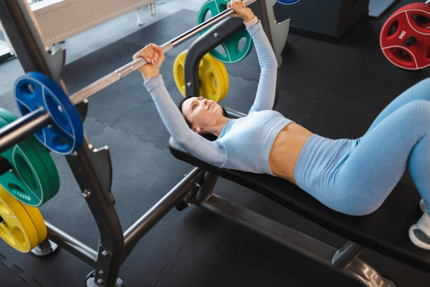 istock Fitness woman lifting barbell while lying on bench 1358752416