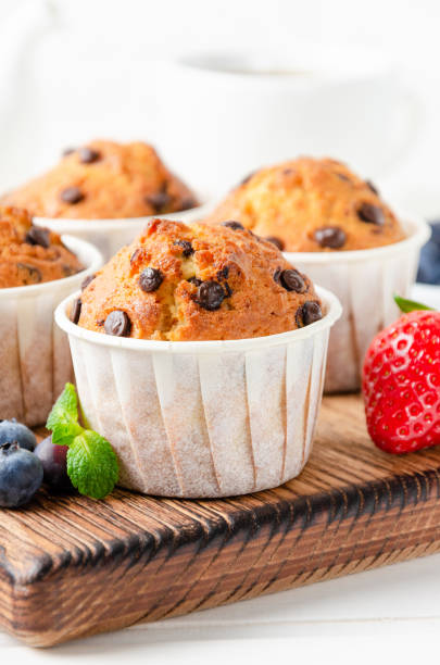istock Muffins with chocolate chips on a wooden bord on a white background with fresh berries. Copy space. 1358754420