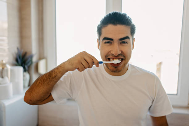 istock Young latin man brushing his teeth 1358755645