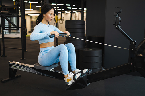 Woman doing exercise on rowing machine in gym