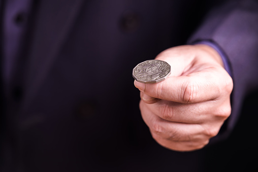 Closeup hand of businessman with coin, going to toss the coin or playing the head or tail, chance, and make a decision