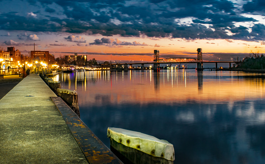 Wilmington's Riverwalk at sunset.  The Cape Fear Bridge reflects off the river.