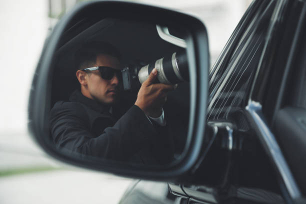 istock Private detective with camera spying from auto, view through car side mirror 1358760349