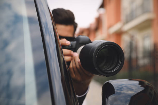 istock Private detective with camera spying from car, focus on lens 1358760606