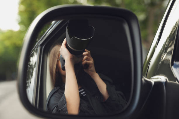 Man sticking out his vintage camera and taking photograph through rear view car mirror