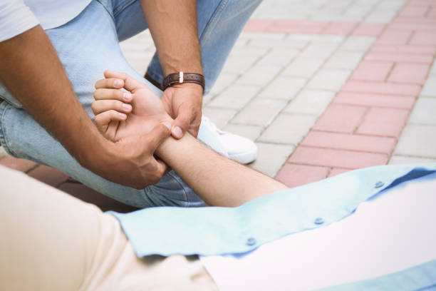 istock Passerby checking pulse of unconscious young man outdoors, closeup. First aid 1358761434