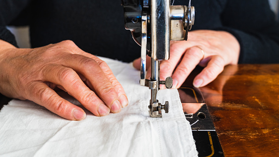 Close-up of woman's hands sewing with old sewing machine.