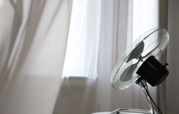istock Modern electric fan on white table near window indoors. Space for text 1358762529
