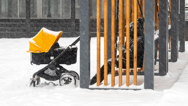 Parent with baby stroller and newborn walking at the city park during winter snowfall Parent with baby stroller and newborn walking at the city park during winter snowfall baby stroller winter stock pictures, royalty-free photos & images