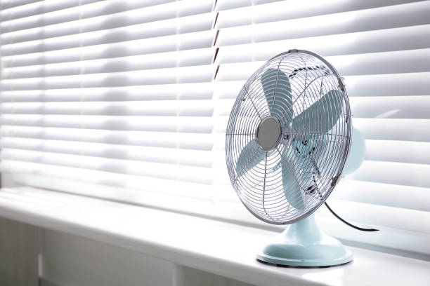 istock Modern electric fan on window sill indoors. Space for text 1358763647