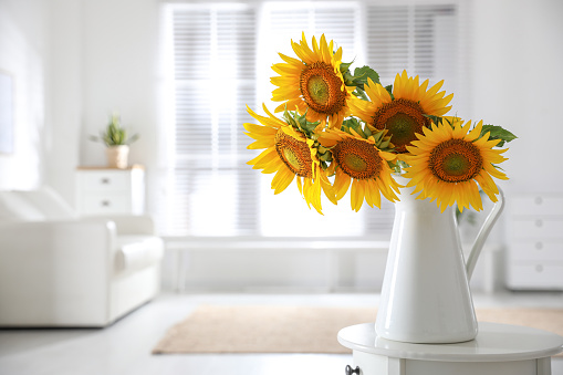 Beautiful bouquet of sunflowers in vase on table indoors. Space for text