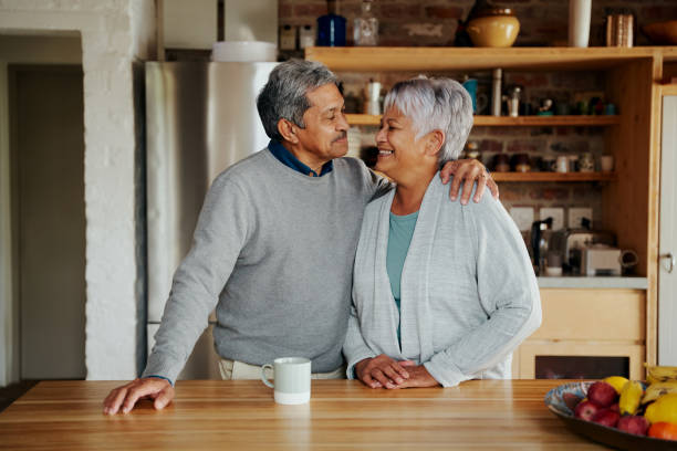 istock Happily retired elderly biracial couple smiling at each other lovingly in modern kitchen. Hugging, living healthy lifestyle in modern kitchen 1358764034