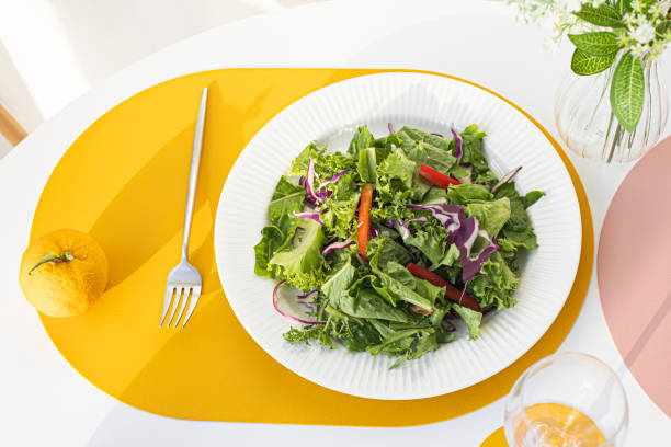 Salad with yellow leather table mat on white table.