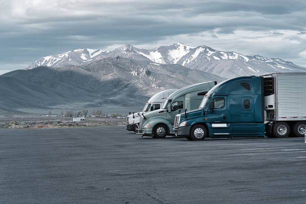 Commercial trucks at a truck stop in Nevada Commercial trucks parked at a truck stop in Nevada with mountain covered in snow seen in the background. trucking stock pictures, royalty-free photos & images