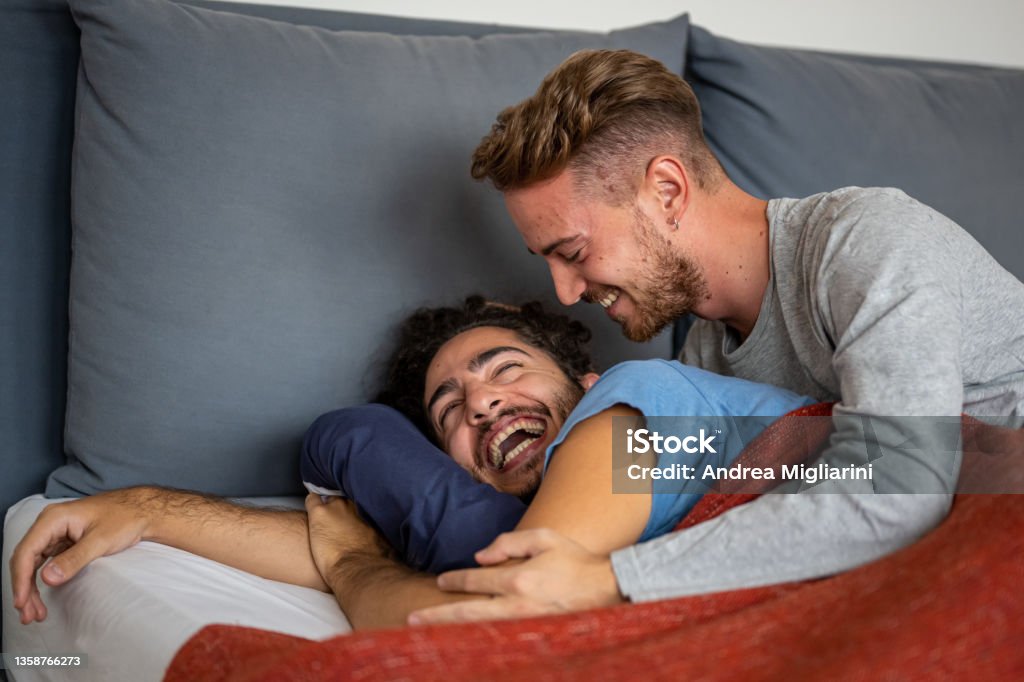 Happy male gay couple on bed at home, couple of smiling married men just woke up in the morning, coming out from the closet concept Couple - Relationship Stock Photo