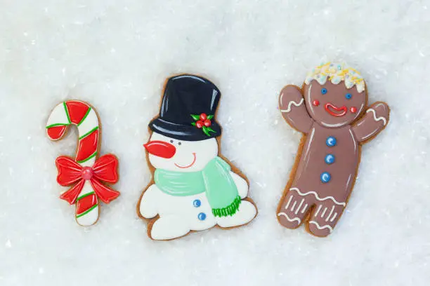 Gingerbread cookies: gingerbreadmen, snowman and candy on white table with snow. Holiday,Christmas and happy New Year. Top view