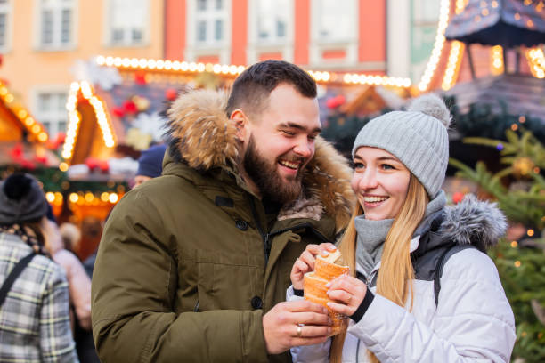 Beautiful couple eating czech Trdelnik on Christmas fair in Wroclaw, Poland stock photo