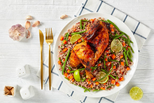 Roasted Half Chicken with brown rice on a platter Roasted Half Chicken with veggie brown riceon a white plate on a wooden table  horizontal view from above, flat lay main course stock pictures, royalty-free photos & images